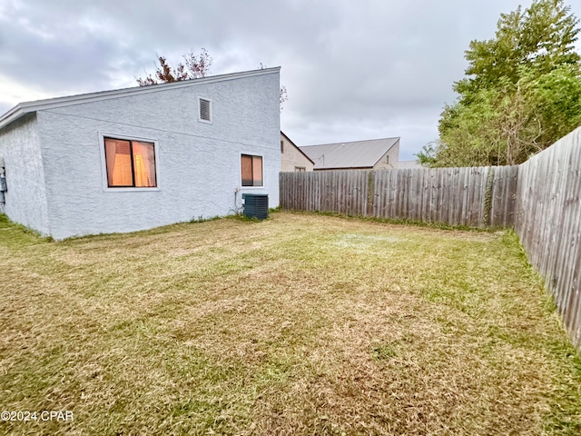 back of house featuring a lawn and cooling unit