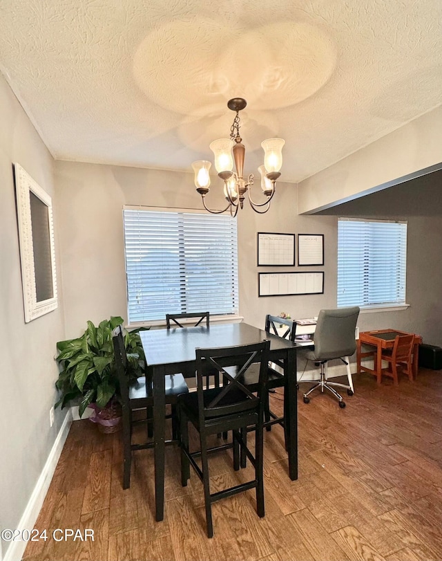 dining area with a wealth of natural light, wood-type flooring, and a notable chandelier