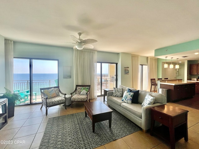 living room with ceiling fan, light tile patterned floors, and a water view