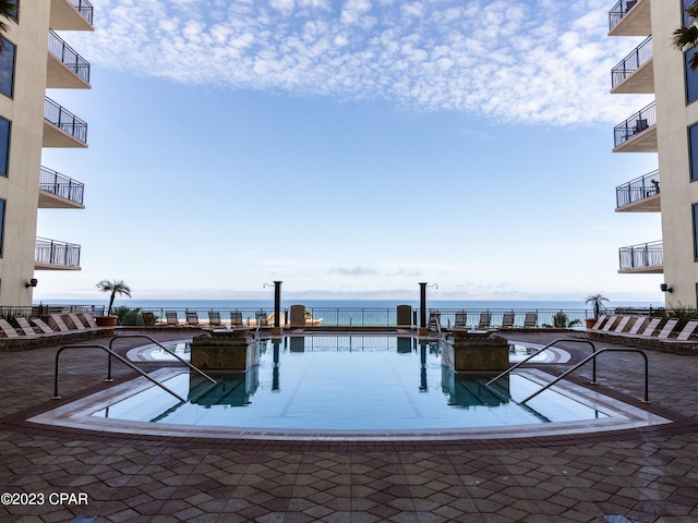 view of pool with a water view and a patio area