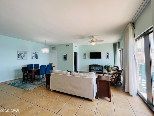 tiled living room with ceiling fan with notable chandelier