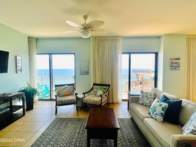 tiled living room with a water view, ceiling fan, and plenty of natural light