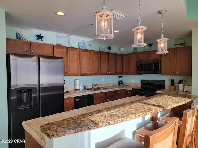 kitchen with black appliances, a breakfast bar, sink, and hanging light fixtures