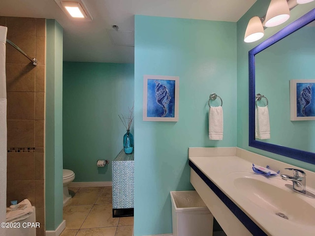 bathroom featuring toilet, tiled shower, tile patterned floors, and sink