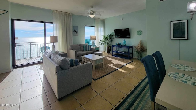 living room featuring ceiling fan, a water view, and light tile patterned floors