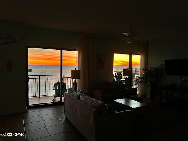 tiled living room featuring ceiling fan and a water view