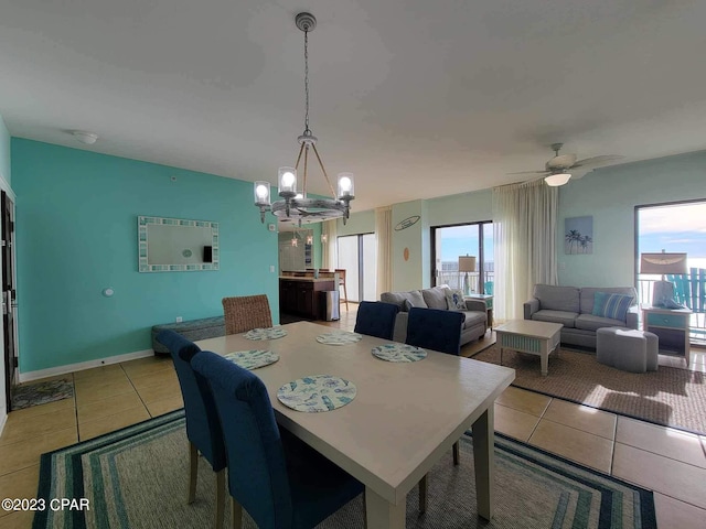 tiled dining space with ceiling fan with notable chandelier