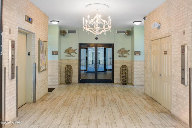8715 Surf Dr Unit 1402B, Panama City, FL 32408 - corridor with brick wall, a chandelier, wood finished floors, french doors, and elevator
