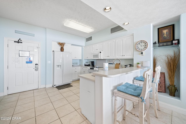 8715 Surf Dr Unit 1402B, Panama City, FL 32408 - kitchen with white appliances, a peninsula, a textured ceiling, light countertops, and light tile patterned floors