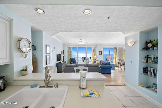 8715 Surf Dr Unit 1402B, Panama City, FL 32408 - kitchen with a sink, a textured ceiling, ceiling fan, light countertops, and built in shelves