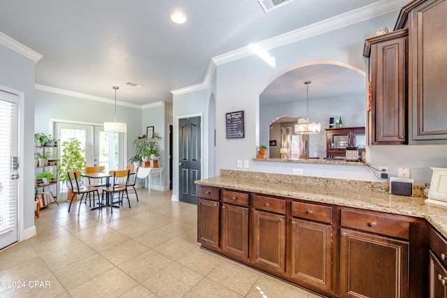 kitchen with light stone countertops, ornamental molding, a textured ceiling, decorative light fixtures, and a chandelier