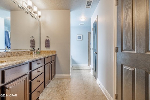 bathroom featuring vanity, a textured ceiling, tile patterned floors, and an enclosed shower