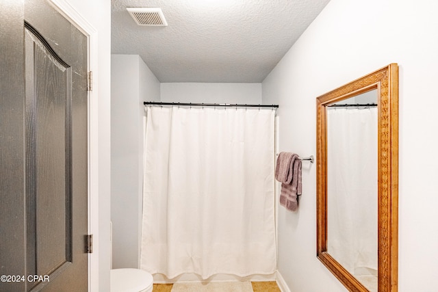 bathroom with toilet and a textured ceiling