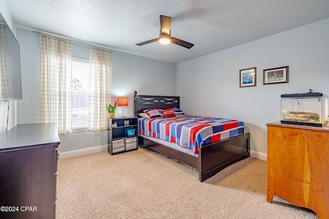 bedroom featuring a textured ceiling, light colored carpet, and ceiling fan