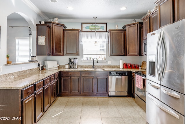 kitchen with sink, hanging light fixtures, stainless steel appliances, crown molding, and a textured ceiling