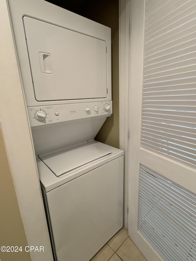 laundry room with light tile patterned floors and stacked washer / drying machine