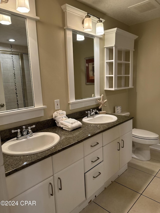 bathroom featuring toilet, vanity, tile patterned floors, and walk in shower