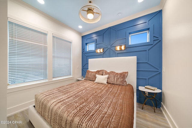 bedroom featuring multiple windows, light hardwood / wood-style flooring, and crown molding