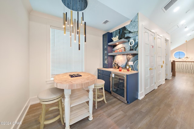 bar featuring dark hardwood / wood-style floors, beverage cooler, pendant lighting, and blue cabinets