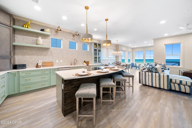 kitchen featuring hanging light fixtures, light wood-type flooring, a water view, and tasteful backsplash