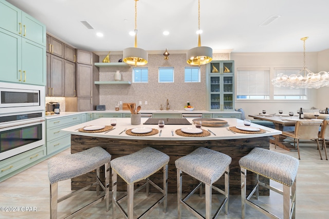 kitchen with backsplash, decorative light fixtures, a kitchen bar, and stainless steel appliances