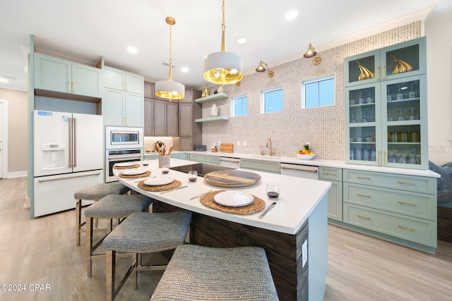 kitchen featuring sink, appliances with stainless steel finishes, tasteful backsplash, decorative light fixtures, and a kitchen island