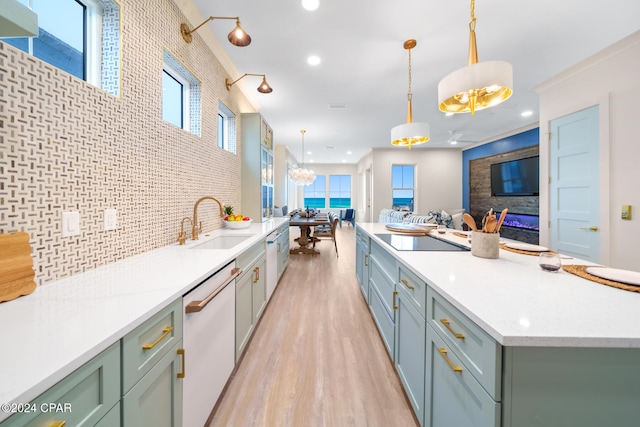 kitchen featuring black electric cooktop, dishwasher, sink, light wood-type flooring, and decorative light fixtures