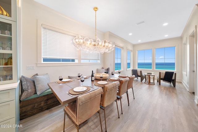 dining space featuring a chandelier, light wood-type flooring, and a water view