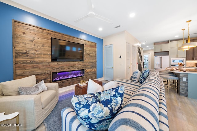 living room with light hardwood / wood-style floors, wooden walls, and crown molding