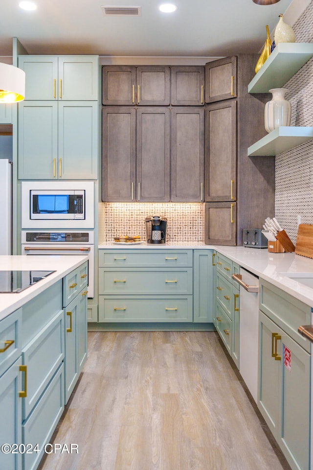 kitchen with white appliances, light hardwood / wood-style flooring, and tasteful backsplash