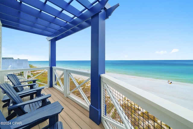 balcony with a beach view, a water view, and a pergola