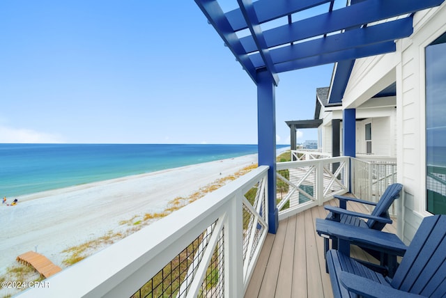 balcony with a view of the beach, a water view, and a pergola