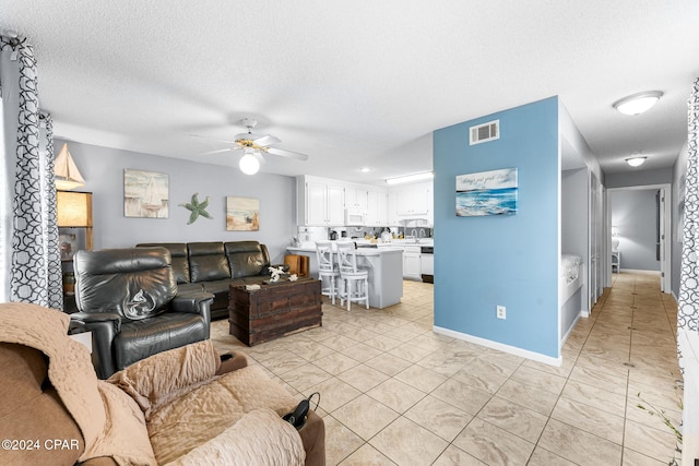 living room featuring a textured ceiling and ceiling fan