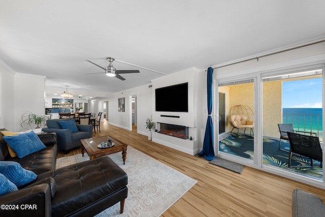 living room featuring light hardwood / wood-style floors, ceiling fan with notable chandelier, and ornamental molding