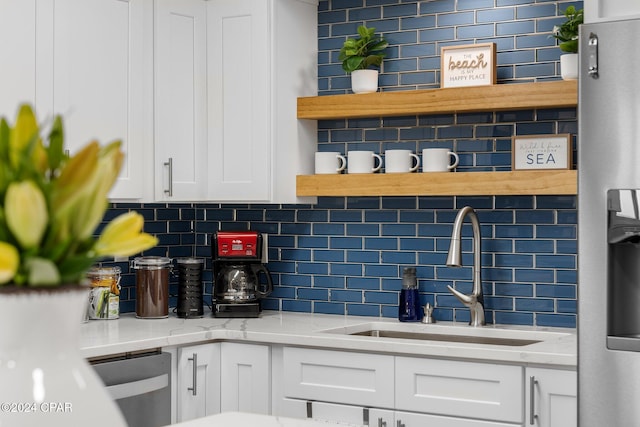 kitchen featuring light stone countertops, dishwasher, sink, decorative backsplash, and white cabinets