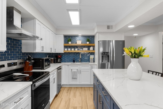 kitchen with white cabinetry, light stone countertops, wall chimney range hood, and appliances with stainless steel finishes