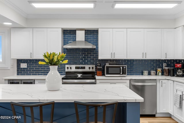 kitchen with wall chimney exhaust hood, stainless steel appliances, a breakfast bar area, decorative backsplash, and ornamental molding