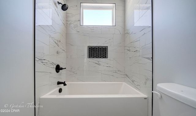 bathroom with tiled shower / bath combo and toilet