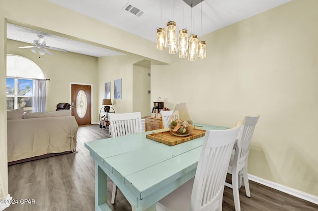 dining space featuring wood-type flooring and ceiling fan with notable chandelier