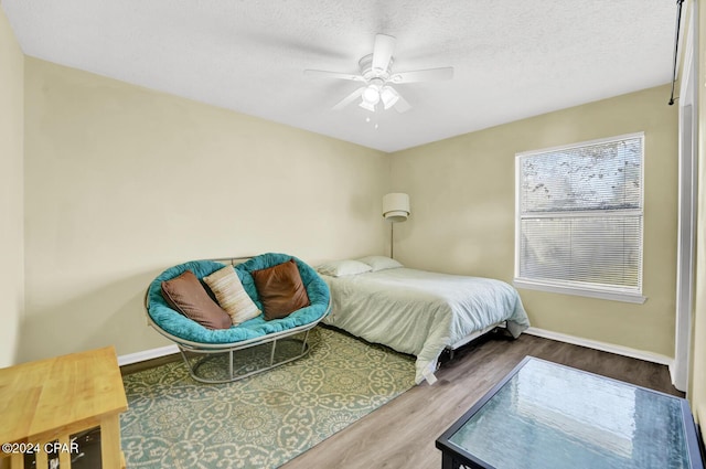 bedroom featuring hardwood / wood-style flooring, a textured ceiling, and ceiling fan