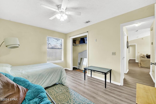 bedroom featuring hardwood / wood-style flooring, a textured ceiling, a closet, and ceiling fan