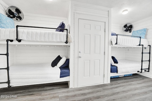 unfurnished bedroom featuring hardwood / wood-style flooring, a textured ceiling, and wood walls