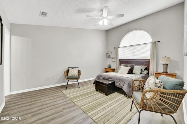 bedroom featuring wood-type flooring, a textured ceiling, and ceiling fan