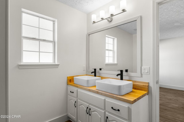 bathroom with hardwood / wood-style floors, vanity, and a textured ceiling