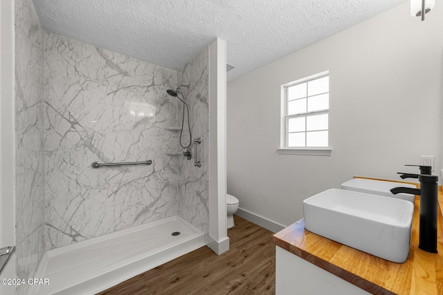 bathroom featuring hardwood / wood-style floors, a tile shower, and a textured ceiling