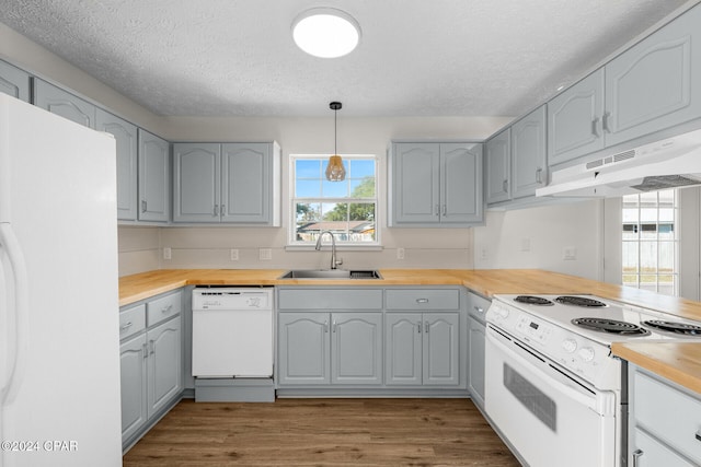 kitchen with butcher block counters, decorative light fixtures, sink, white appliances, and light hardwood / wood-style flooring