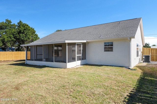 rear view of property featuring central AC unit, a lawn, and a sunroom