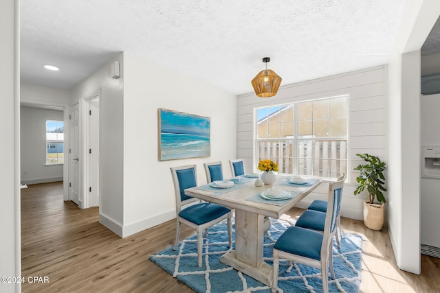 dining room with a textured ceiling and light hardwood / wood-style floors