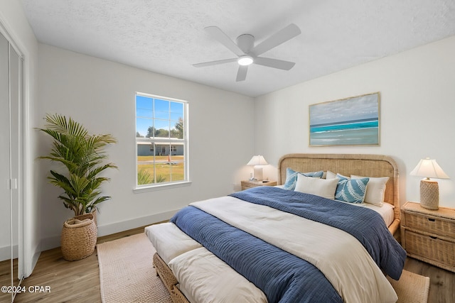 bedroom with ceiling fan, a textured ceiling, and light hardwood / wood-style flooring