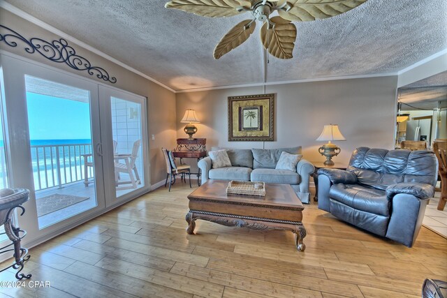 living room with a water view, a textured ceiling, light hardwood / wood-style flooring, crown molding, and french doors